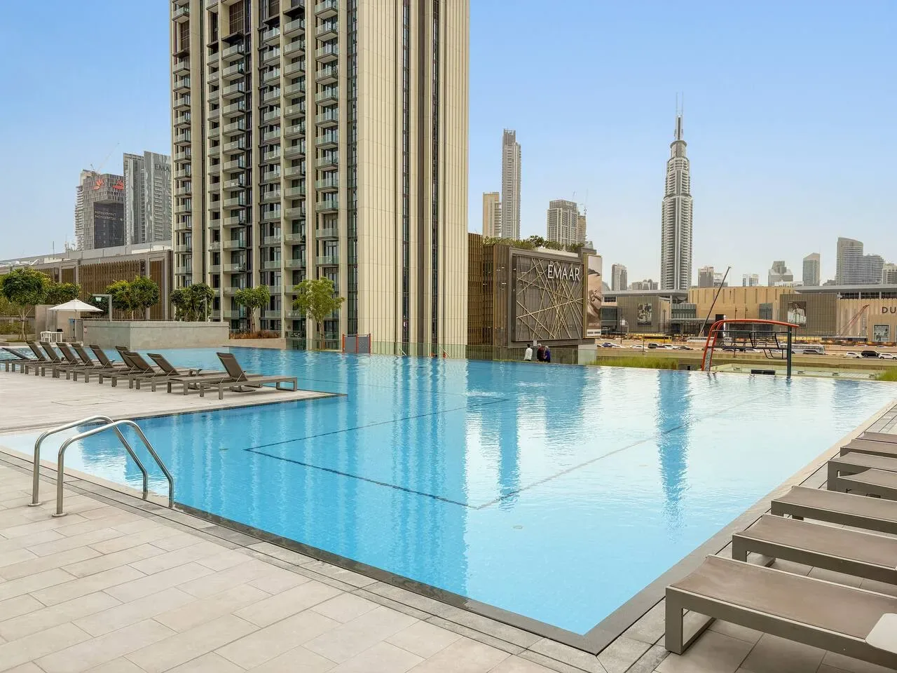 Una piscina en la azotea ofrece vistas de edificios altos bajo un cielo despejado.