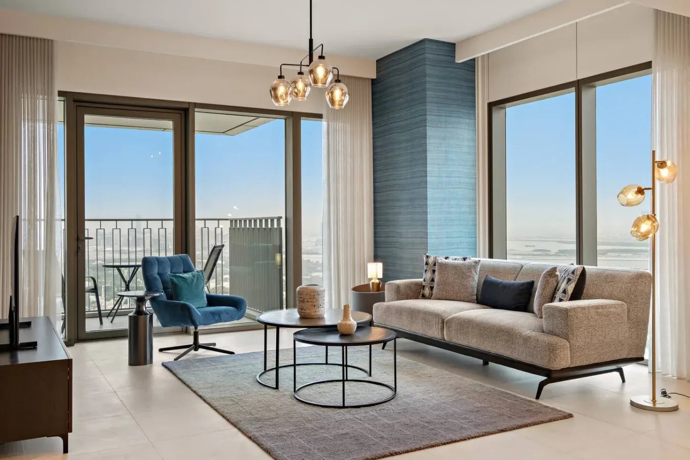 A bright living room with seating beside large windows overlooking the water.
