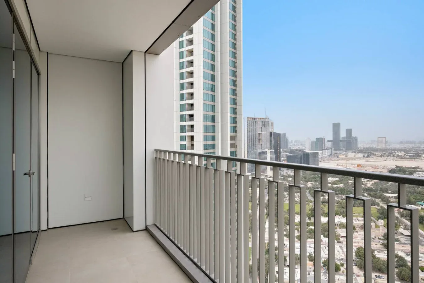 Un balcón con barandilla metálica ofrece vistas de edificios y del horizonte urbano.