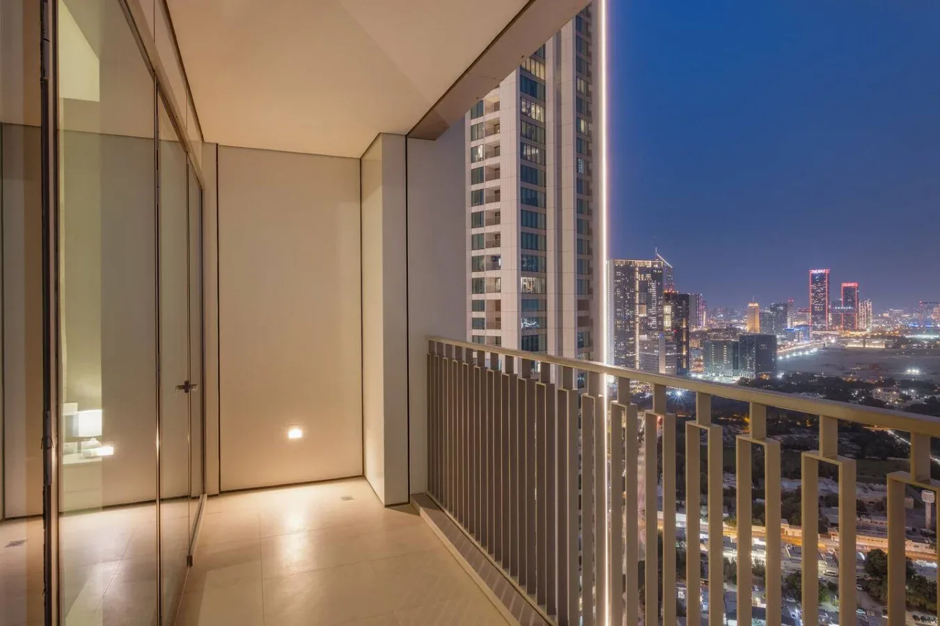 Un balcón de noche ofrece vistas de edificios iluminados de la ciudad.