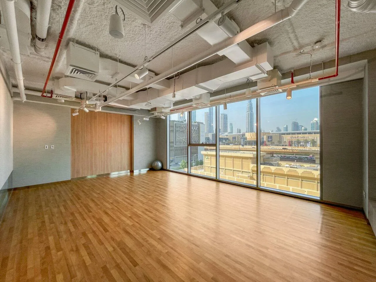 Una sala vacía con suelo de madera y grandes ventanas con vistas a la ciudad.
