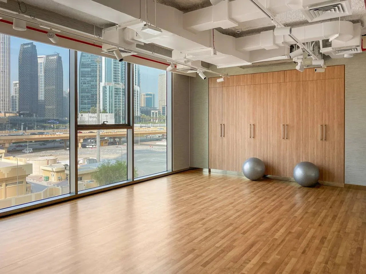 Un amplio estudio con suelo de madera y grandes ventanales con vistas a edificios de la ciudad.