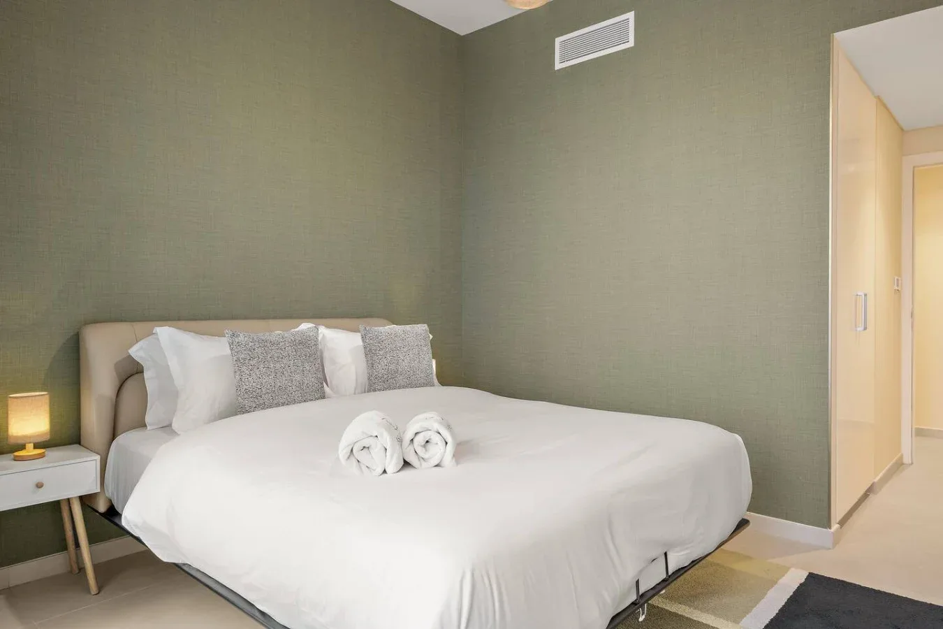 Un dormitorio con una cama tendida y una puerta abierta a un pasillo.