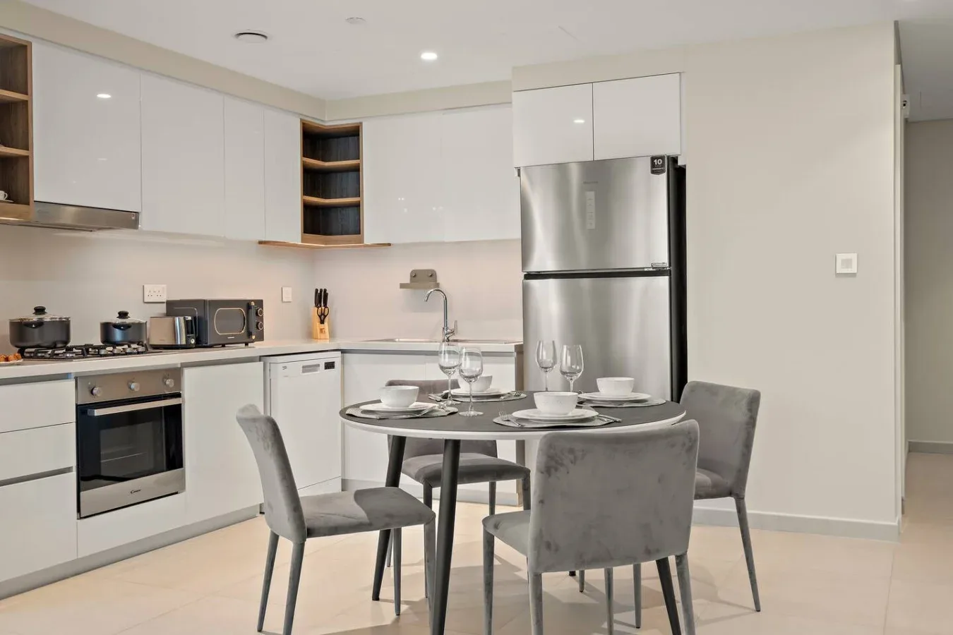 Una cocina luminosa con comedor y una mesa redonda preparada para comer.