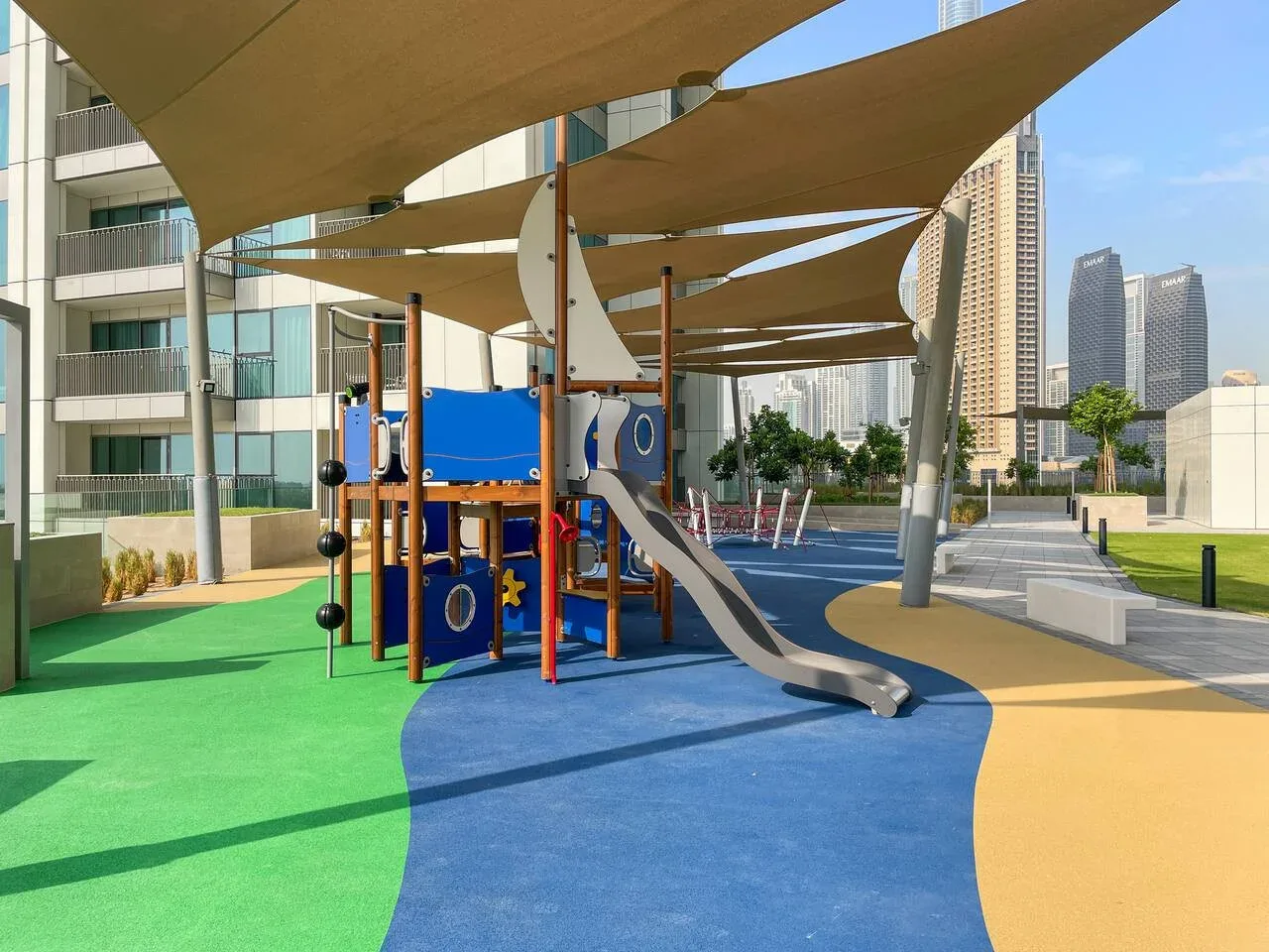 Un parque infantil al aire libre con juegos coloridos y suelo de caucho.