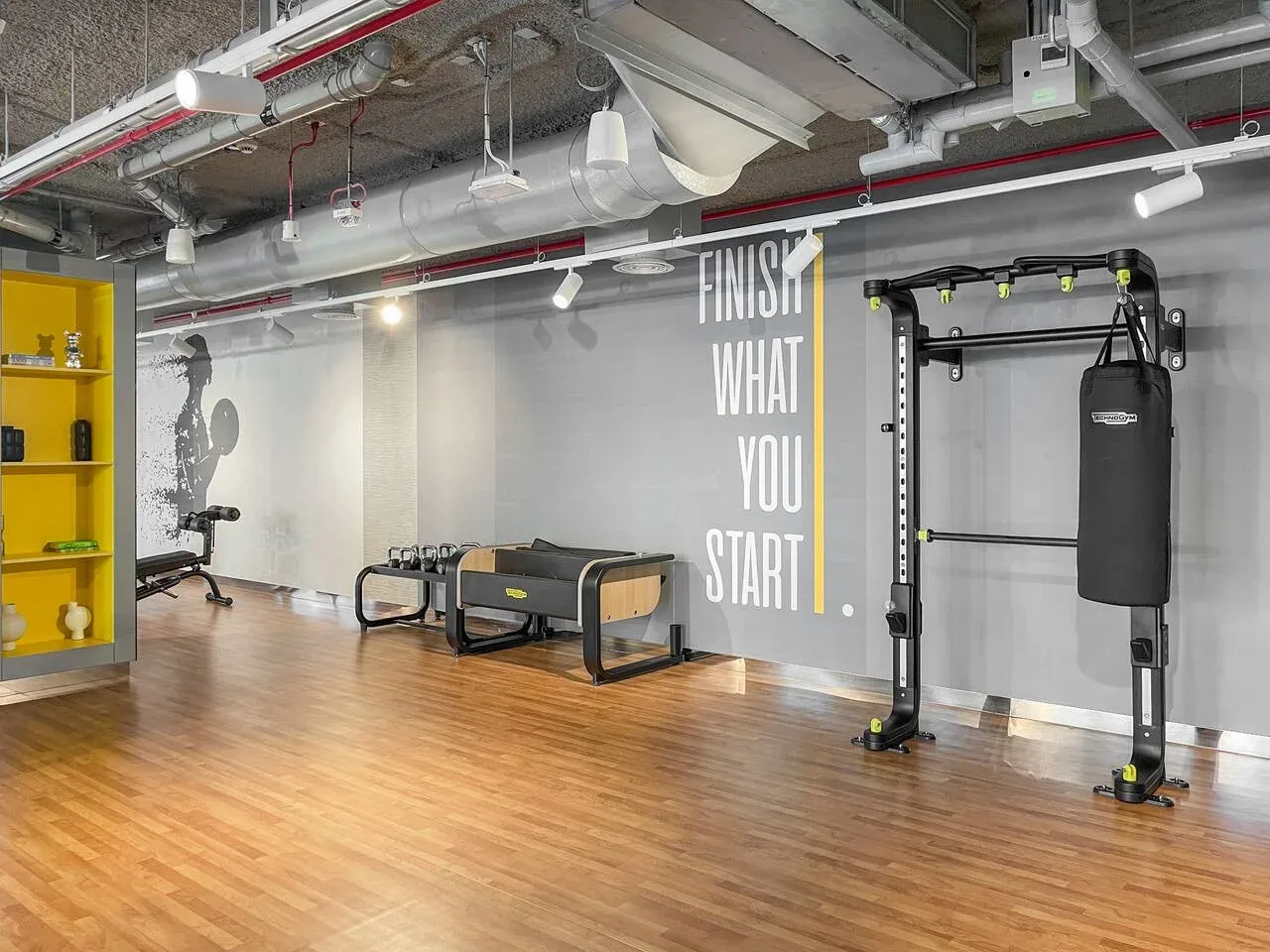 Una sala de ejercicio con equipos y una frase motivadora en la pared.