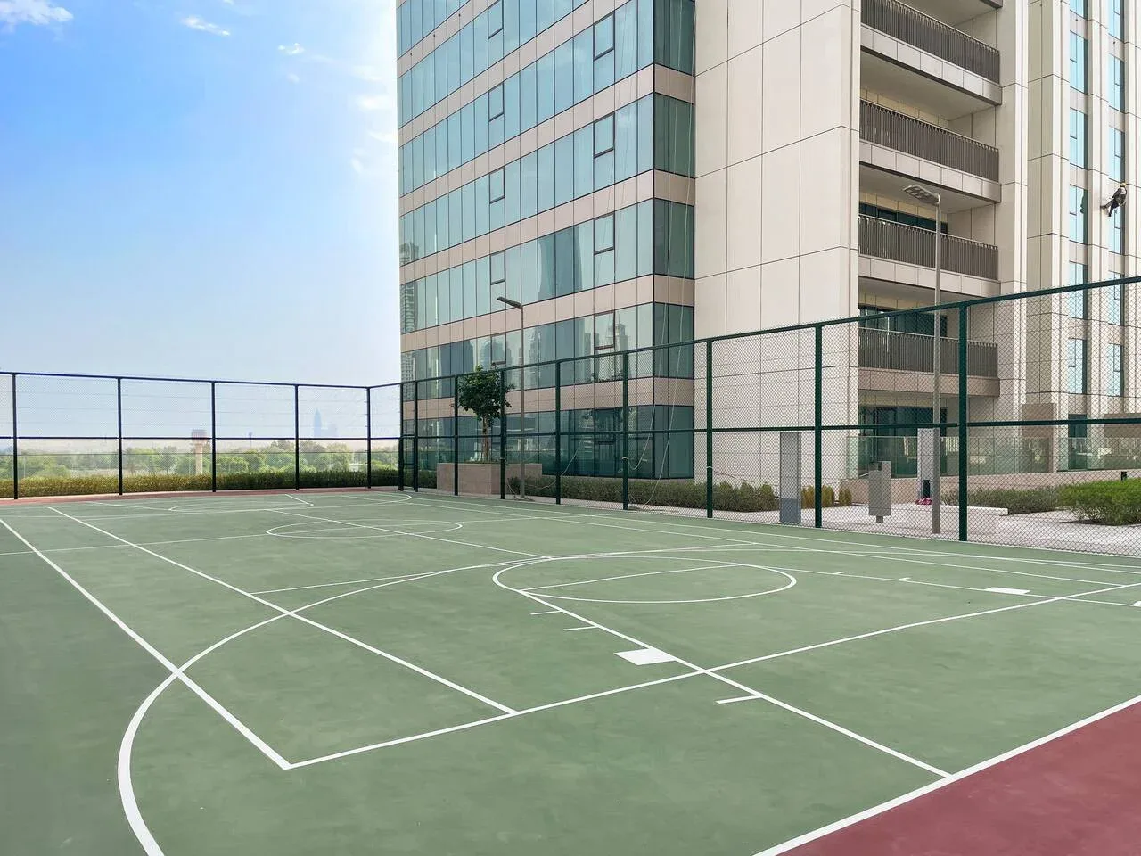 Una cancha deportiva al aire libre con líneas pintadas está junto a un edificio moderno.
