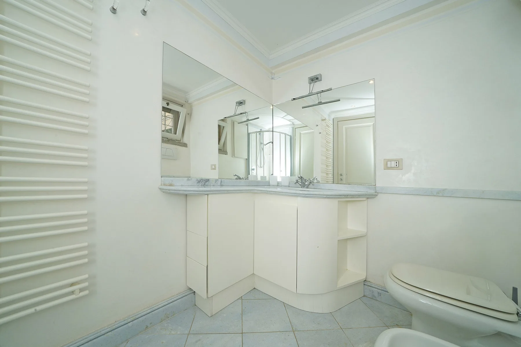 A bright bathroom with a mirrored vanity and a toilet.