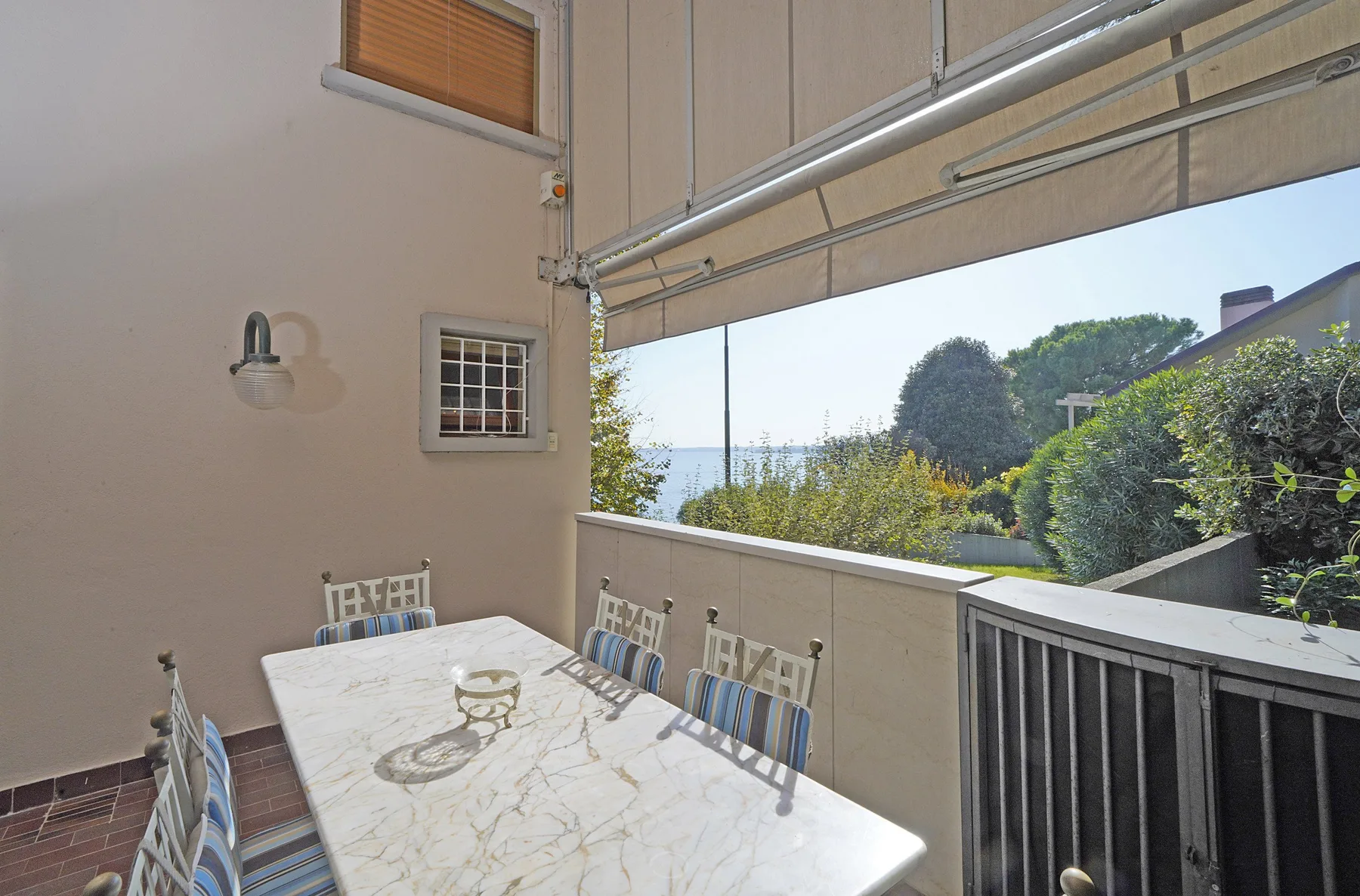 A covered outdoor dining area with a table overlooking greenery and distant water.