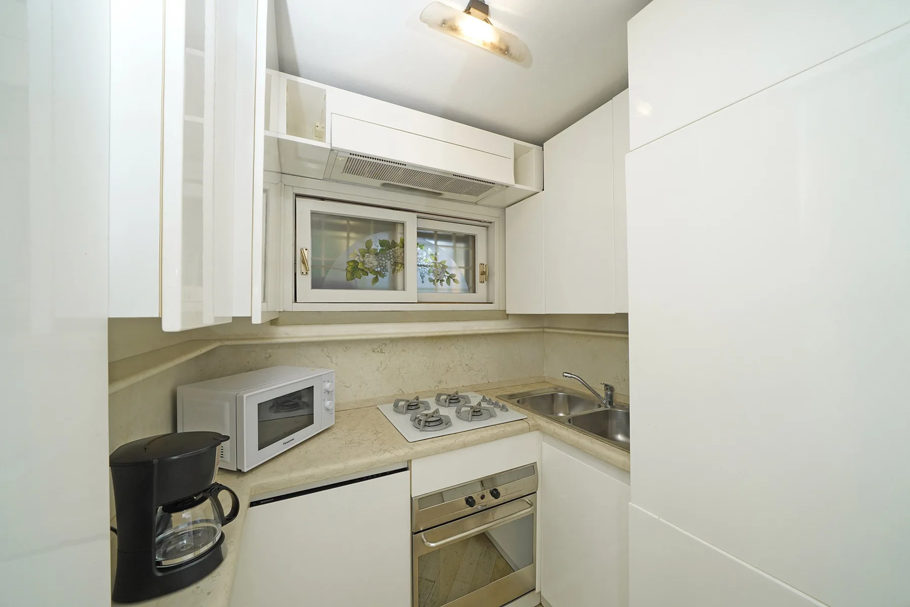 A compact kitchen with white cabinets, a countertop, and cooking appliances.