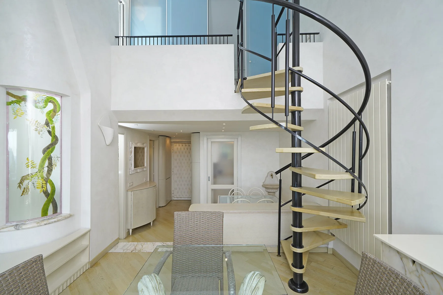 A bright interior with a spiral staircase and a dining area.