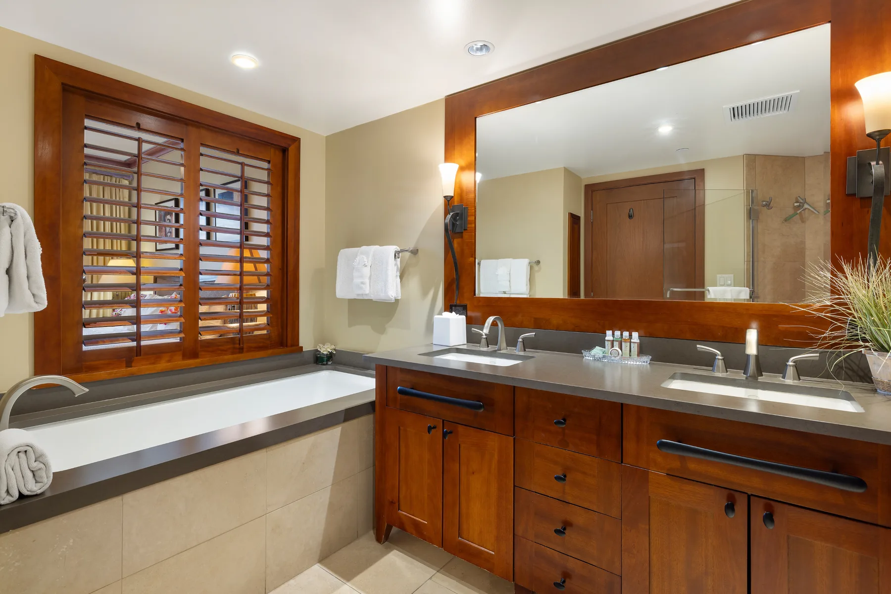 Un lavabo de baño con un espejo amplio junto a una bañera empotrada.
