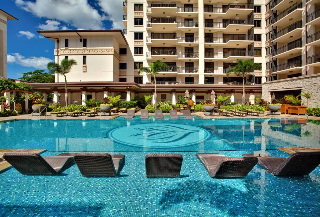 Una gran piscina al aire libre se encuentra frente a un edificio de varios pisos.