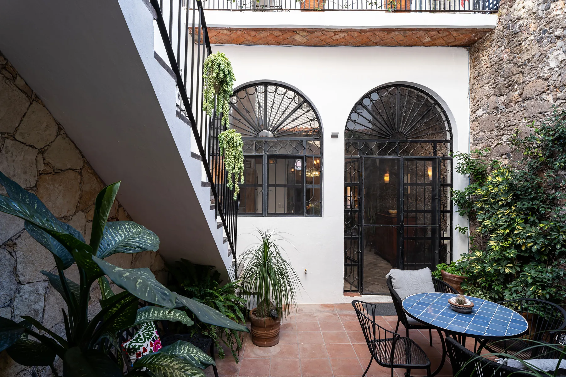 A courtyard patio has arched windows and a round outdoor table.