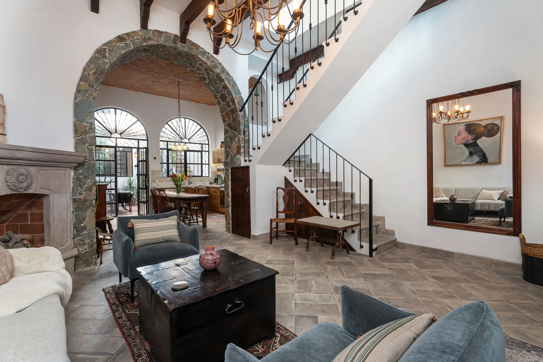 A living room with seating, a stone archway, and a staircase.