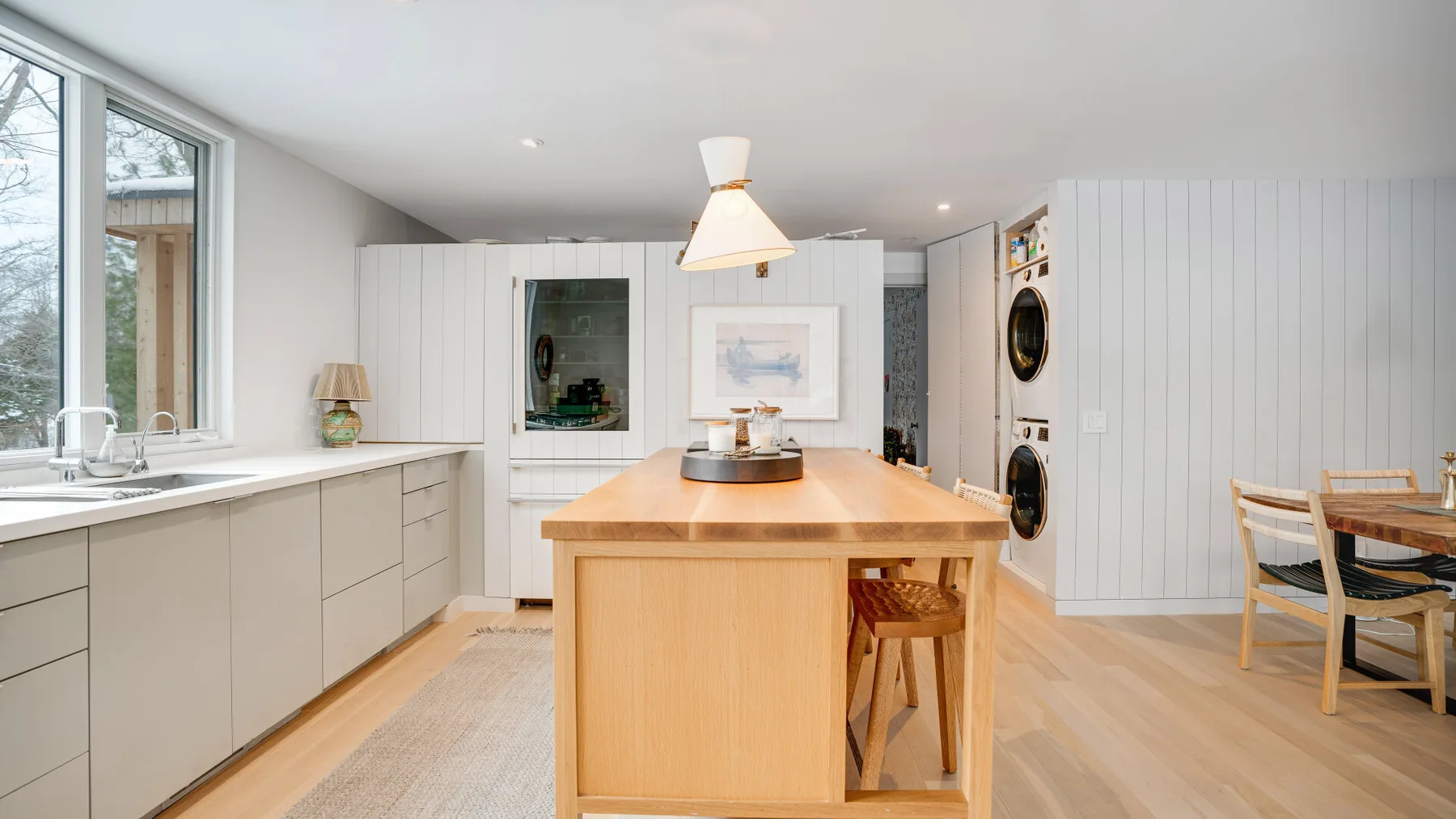 A bright kitchen with a central island, pale cabinetry, and a dining area.