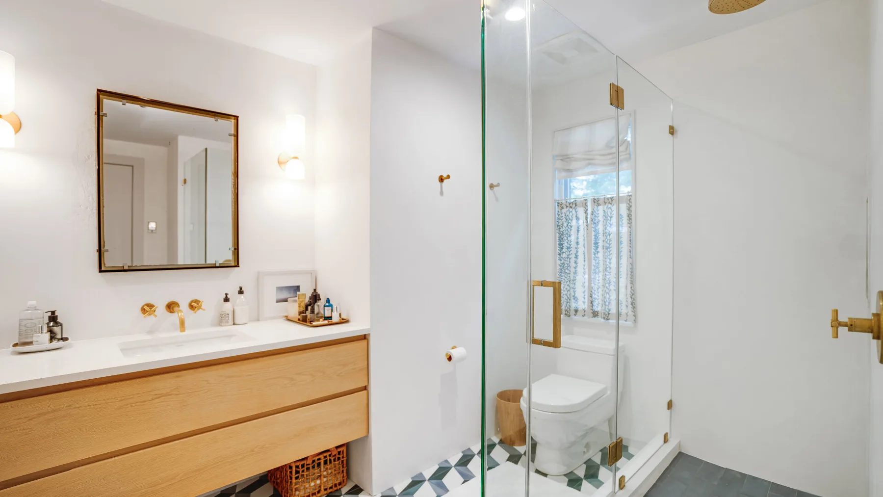 A bright bathroom with a long vanity and a glass shower.