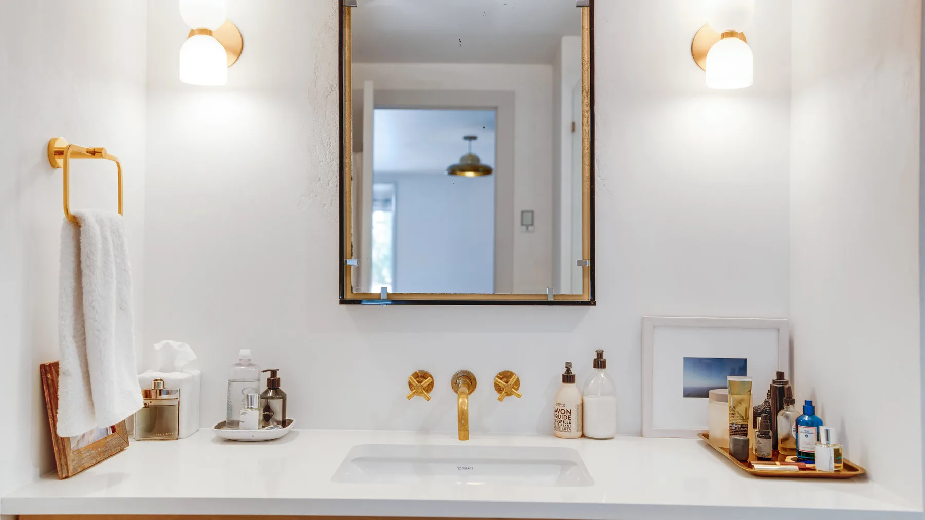 A bright bathroom vanity with a sink, mirror, and wall lights.