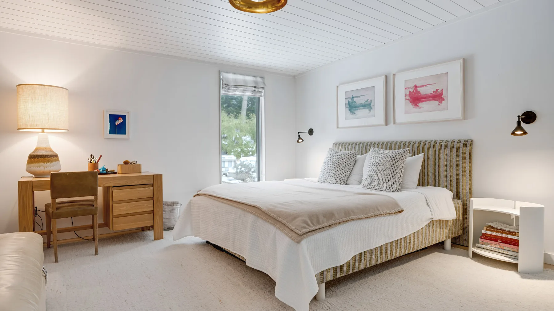 A bright bedroom with a large bed, bedside tables, and framed artwork.