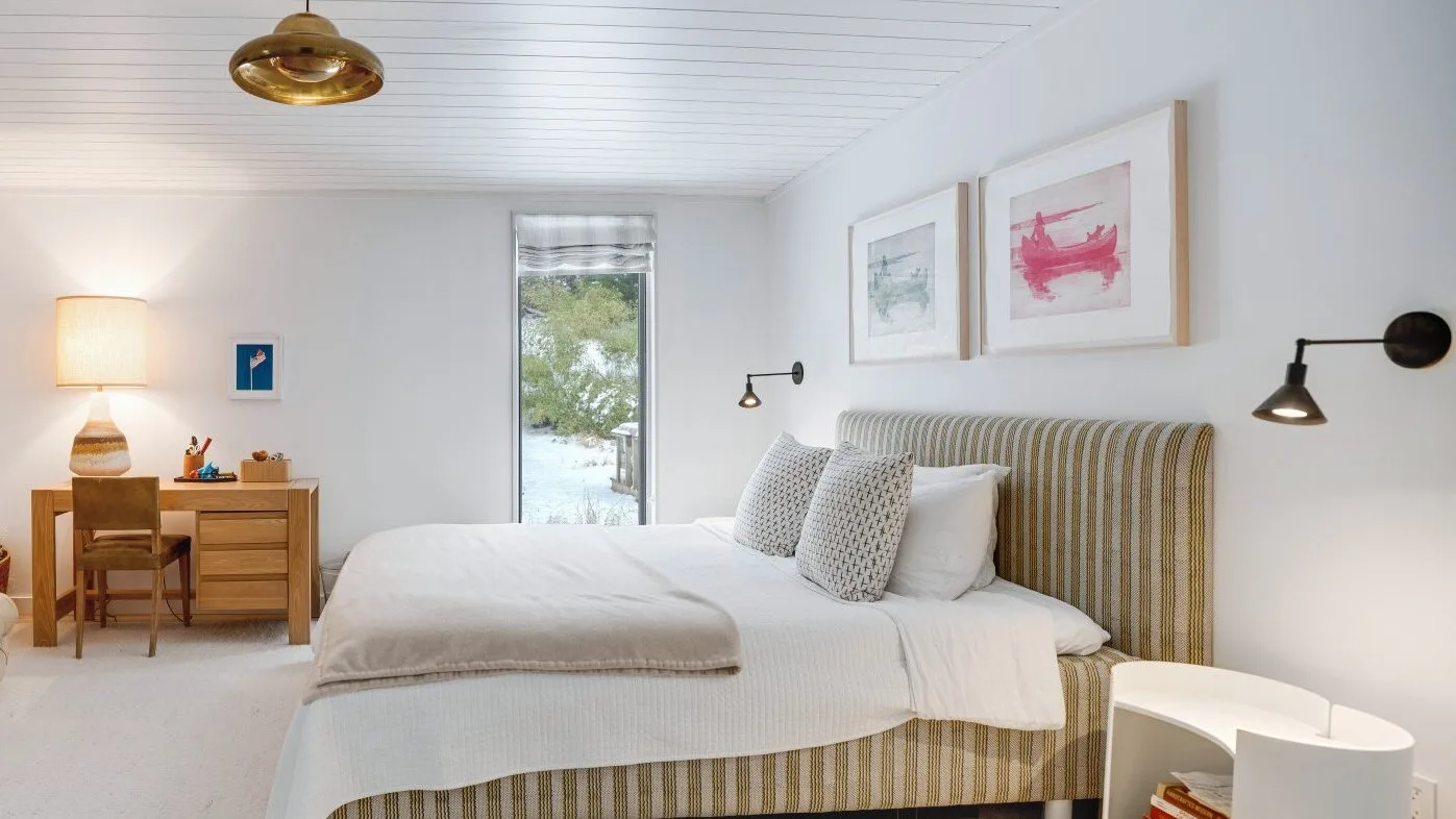 A bright bedroom features a neatly made bed and a small desk by the window.