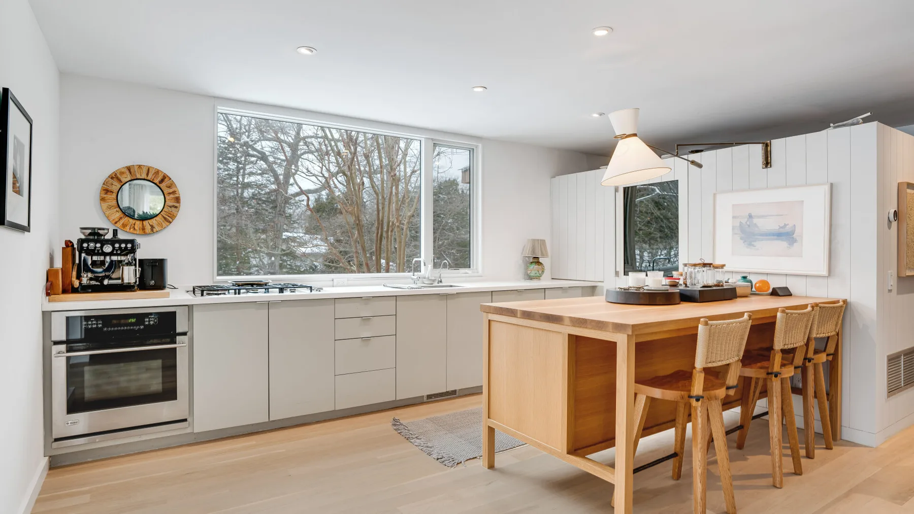 A bright modern kitchen with a central island and large windows.