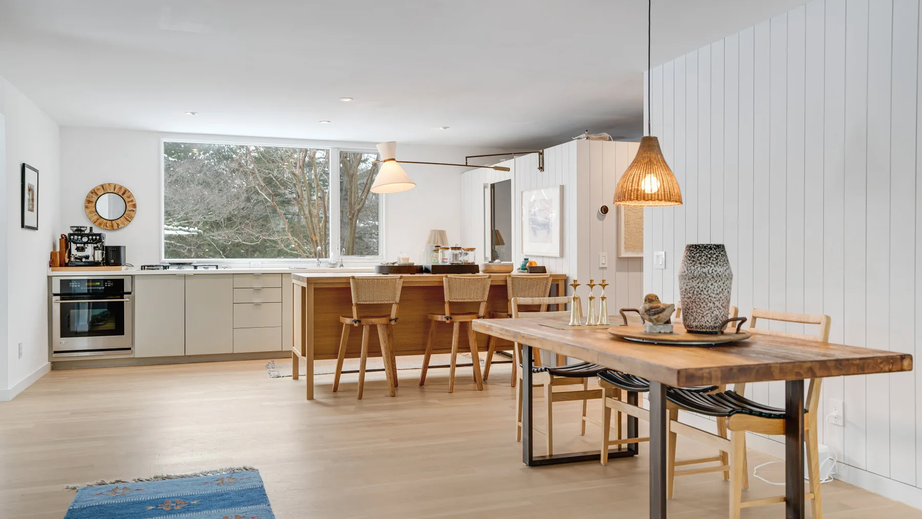 An open-plan kitchen and dining area with a long wooden table and pale cabinetry.