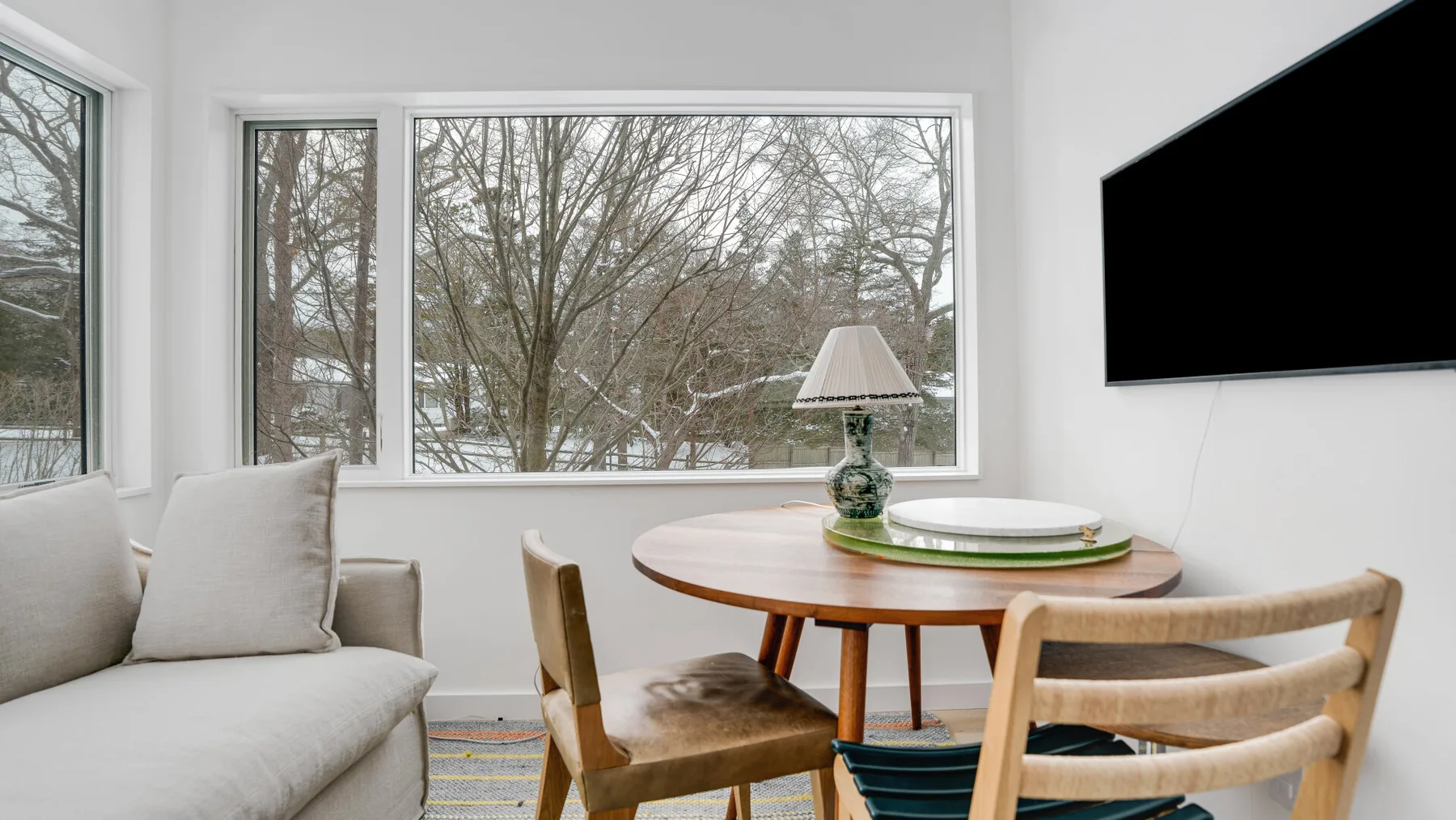 A bright dining area with a round table, seating, and large windows.