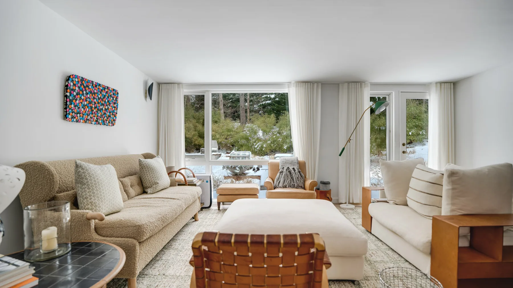 A bright living room with seating around a low table and wide windows.
