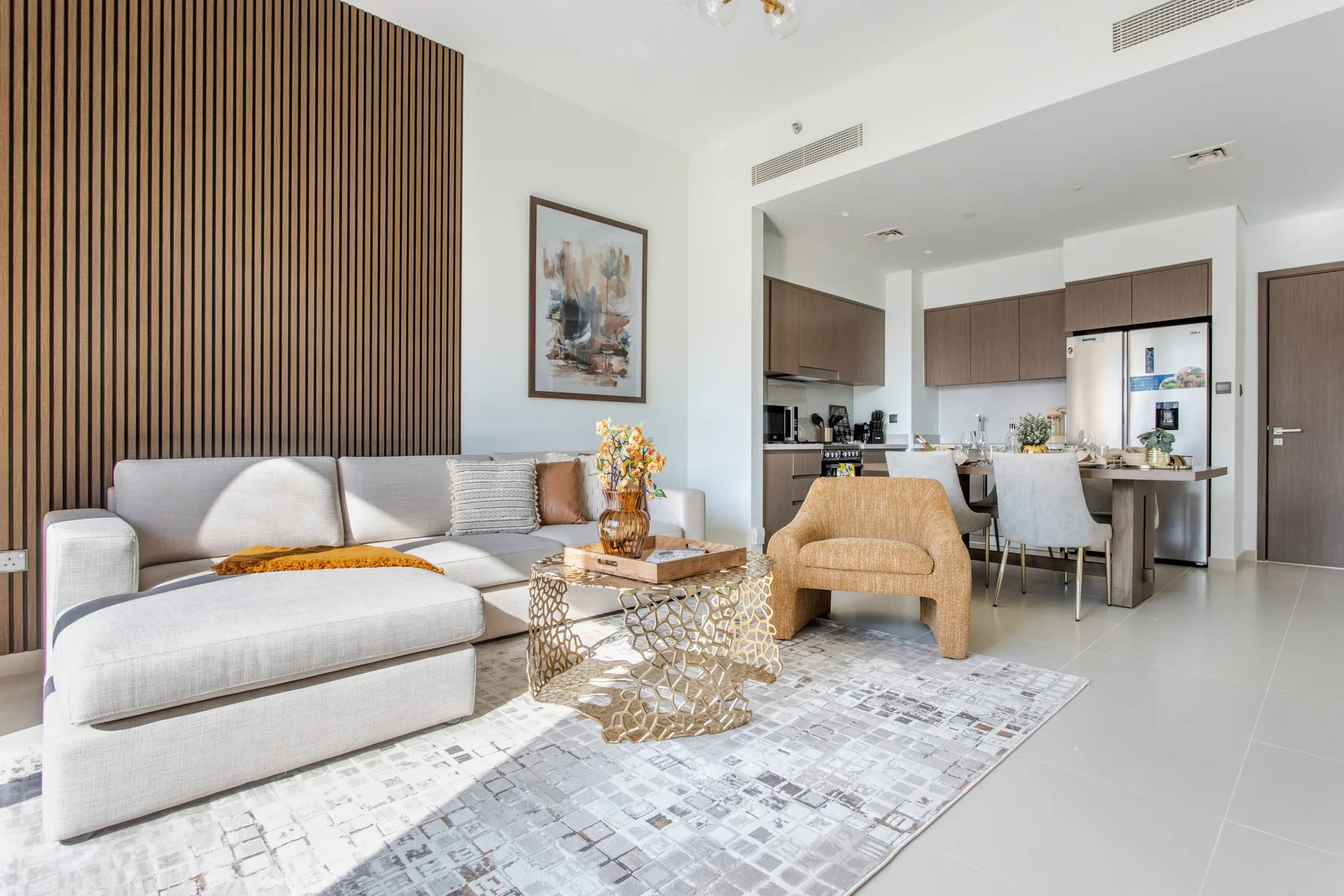Una sala luminosa con asientos, una mesa de centro y una cocina-comedor abierta.