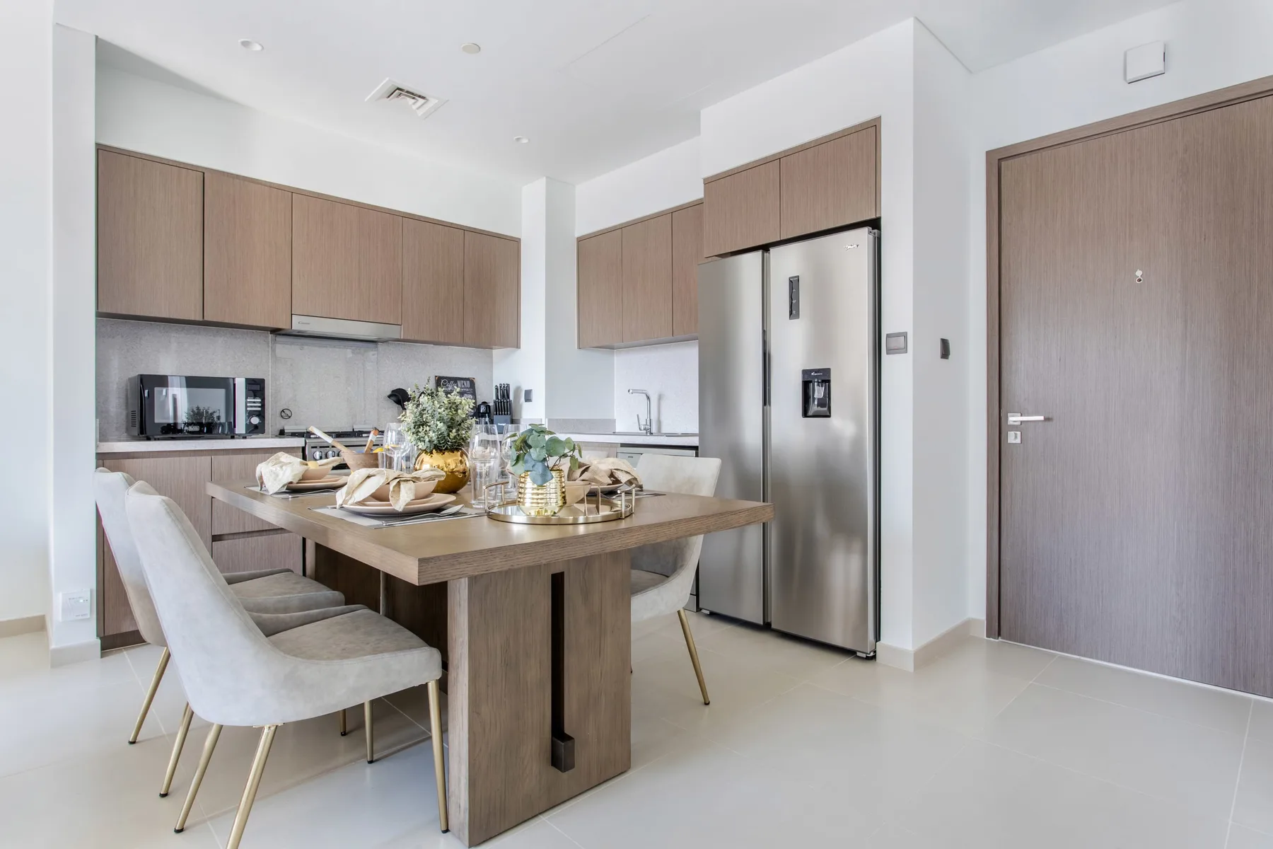 Cocina y comedor modernos con gabinetes de madera y una mesa preparada para comer.