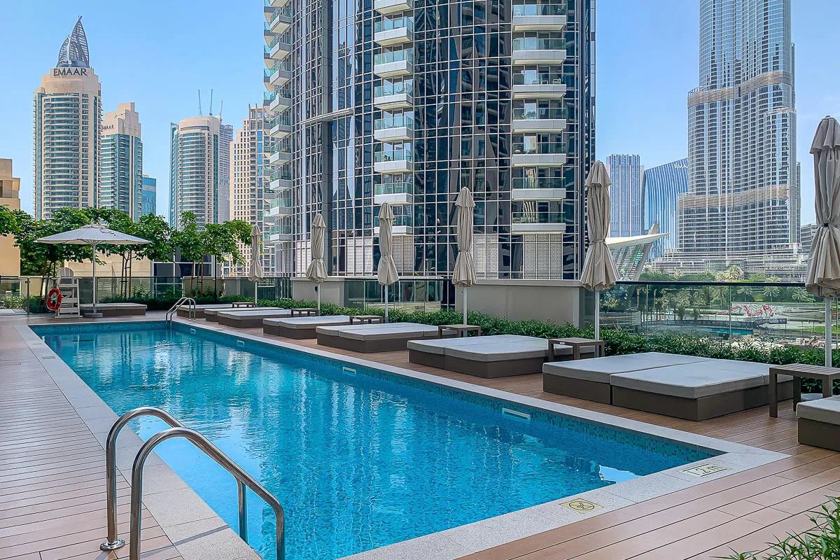 Una piscina en la azotea está rodeada de asientos y altos edificios urbanos.