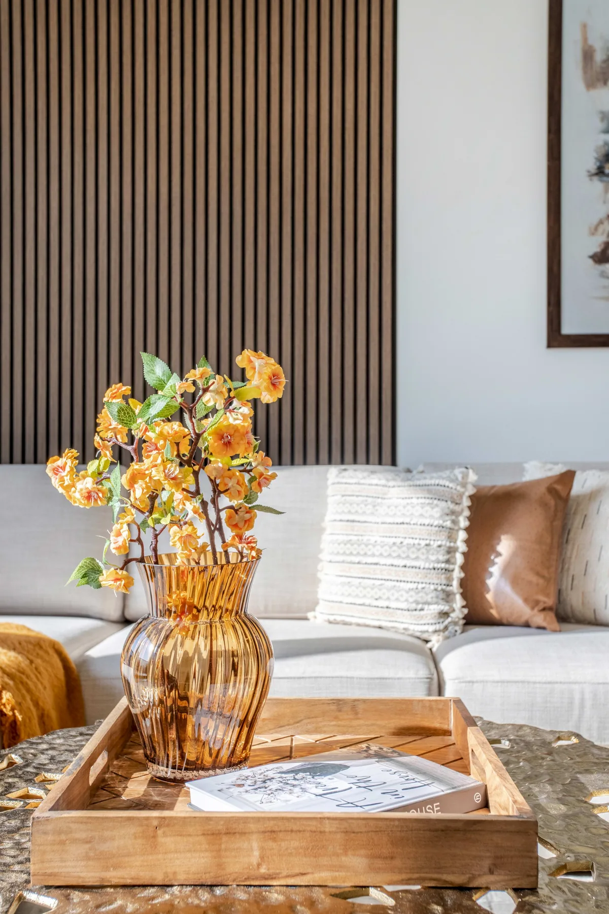 Una zona de estar con un jarrón de flores amarillas sobre una bandeja de madera.