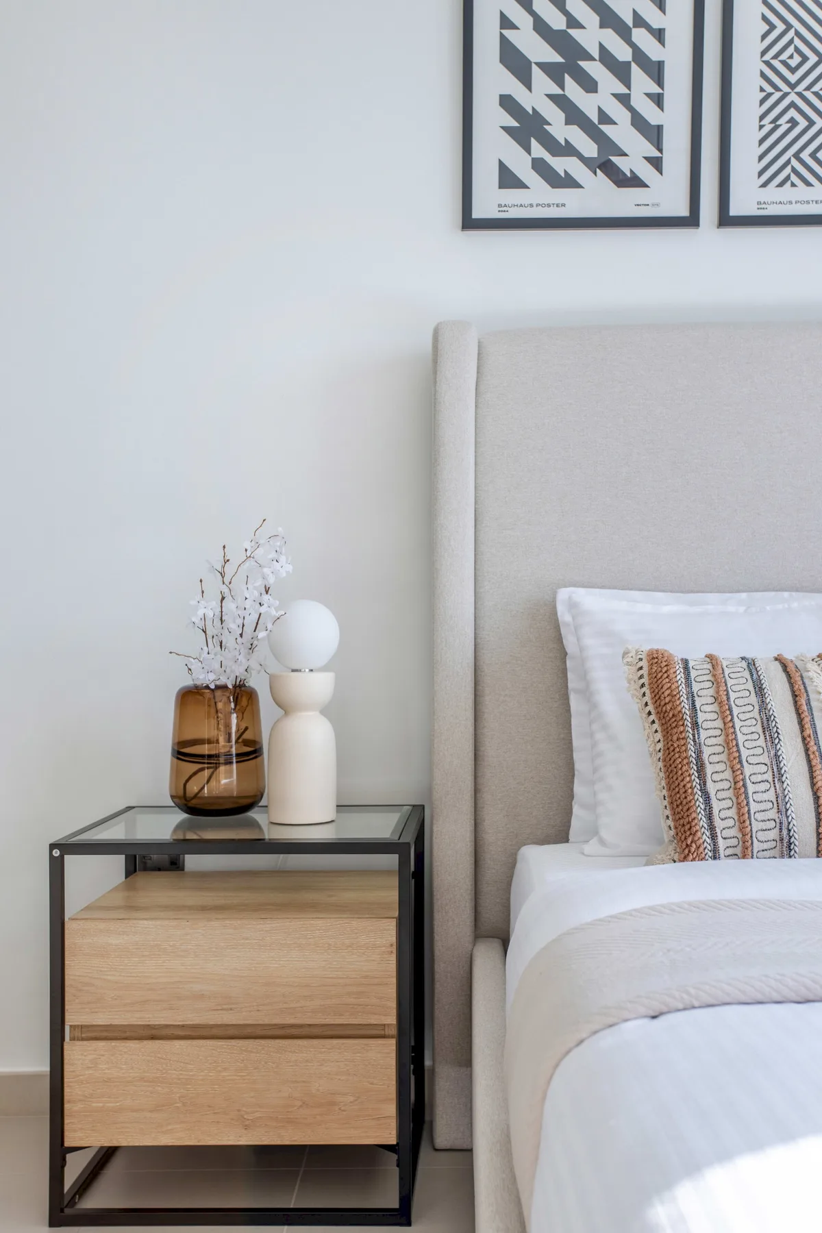 Un dormitorio con una cama, un cojín estampado y una mesita de noche.