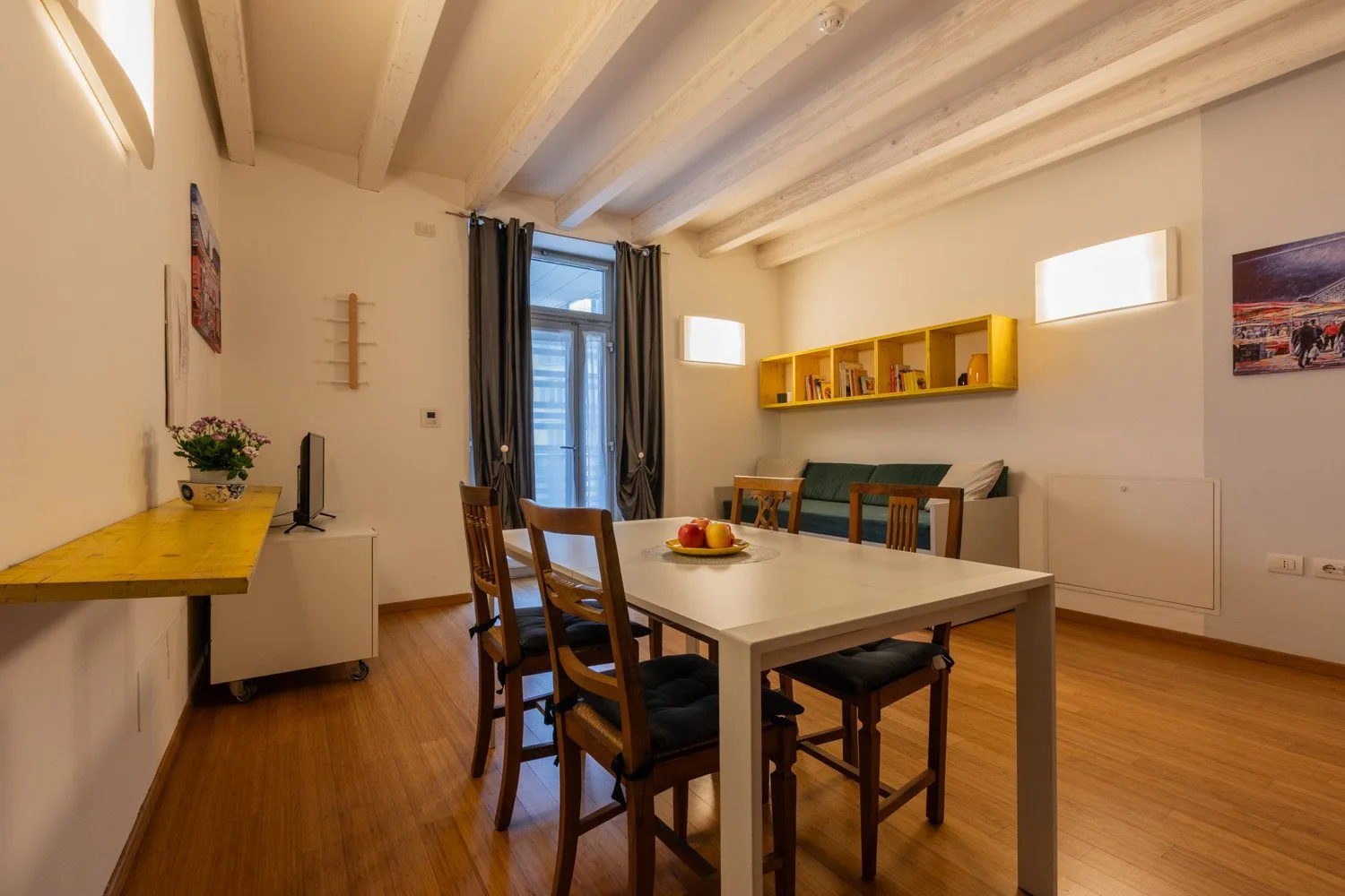 Un comedor con una mesa y sillas junto a una ventana y estantes.