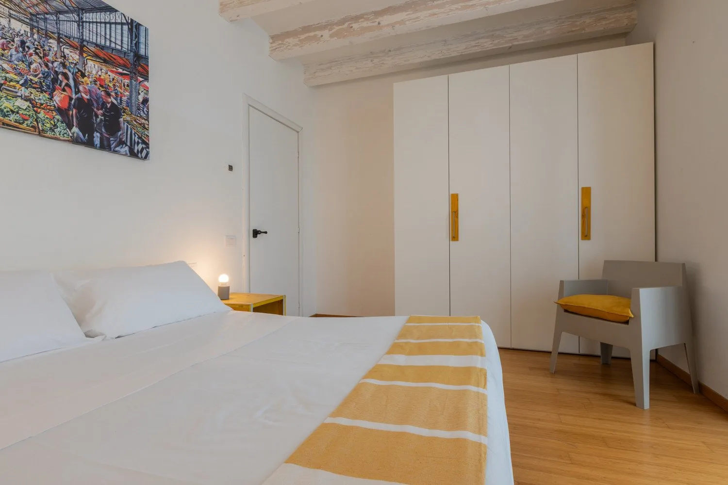 Un dormitorio con una cama bien tendida, un armario y una silla.