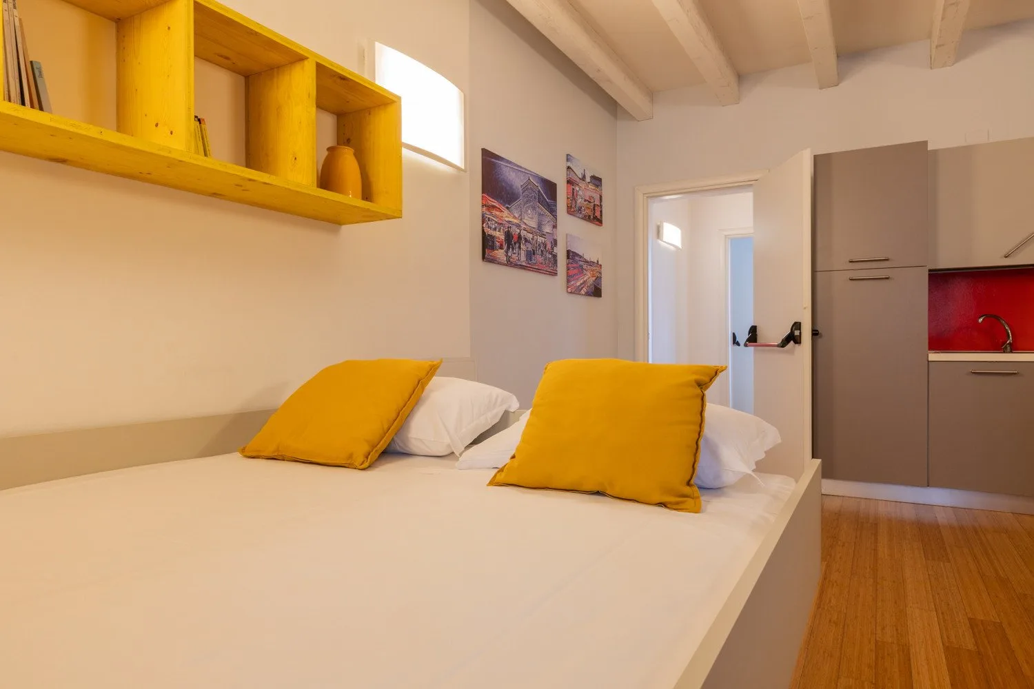 Un dormitorio con una cama vestida de blanco y almohadas amarillo mostaza.