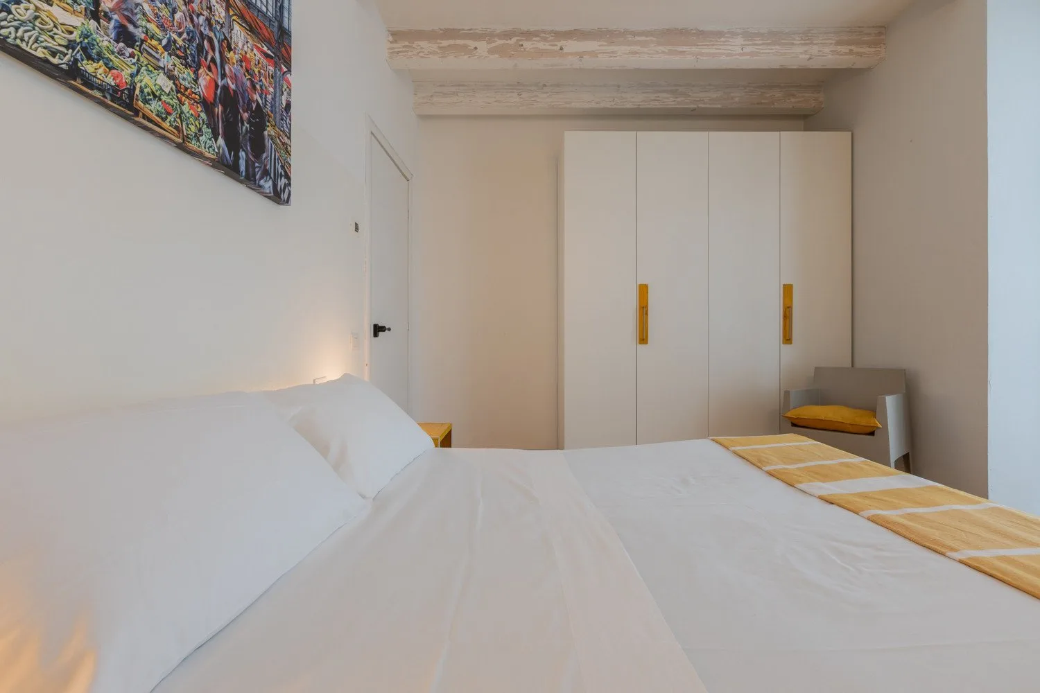 Un dormitorio con una cama tendida y un armario blanco.