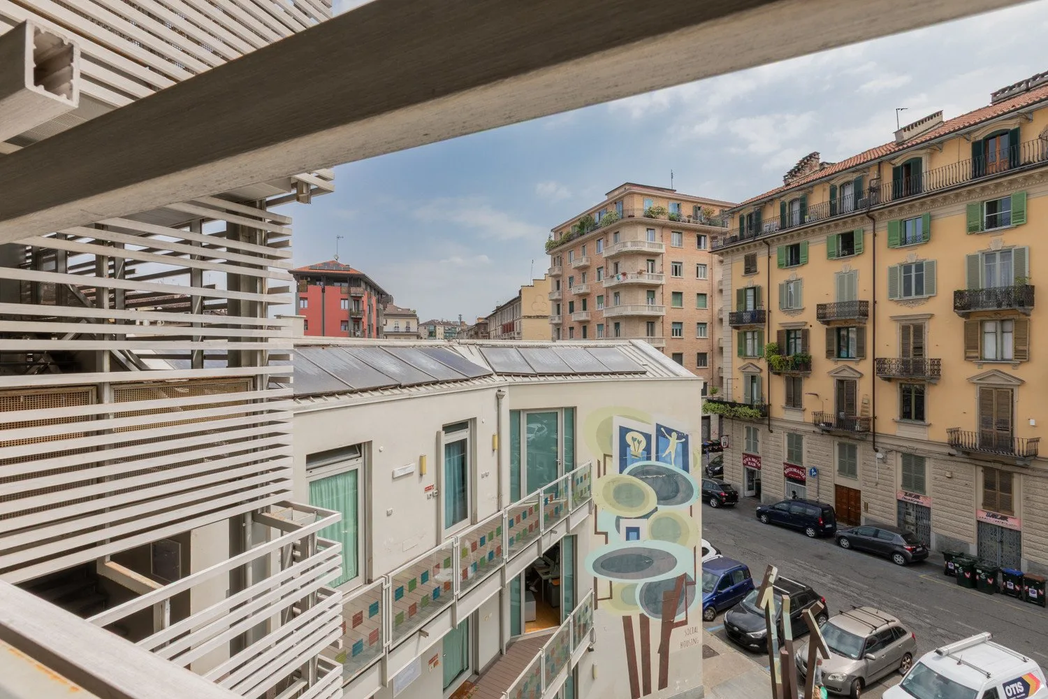 Una calle urbana vista desde un edificio moderno, con balcones y fachadas de apartamentos.