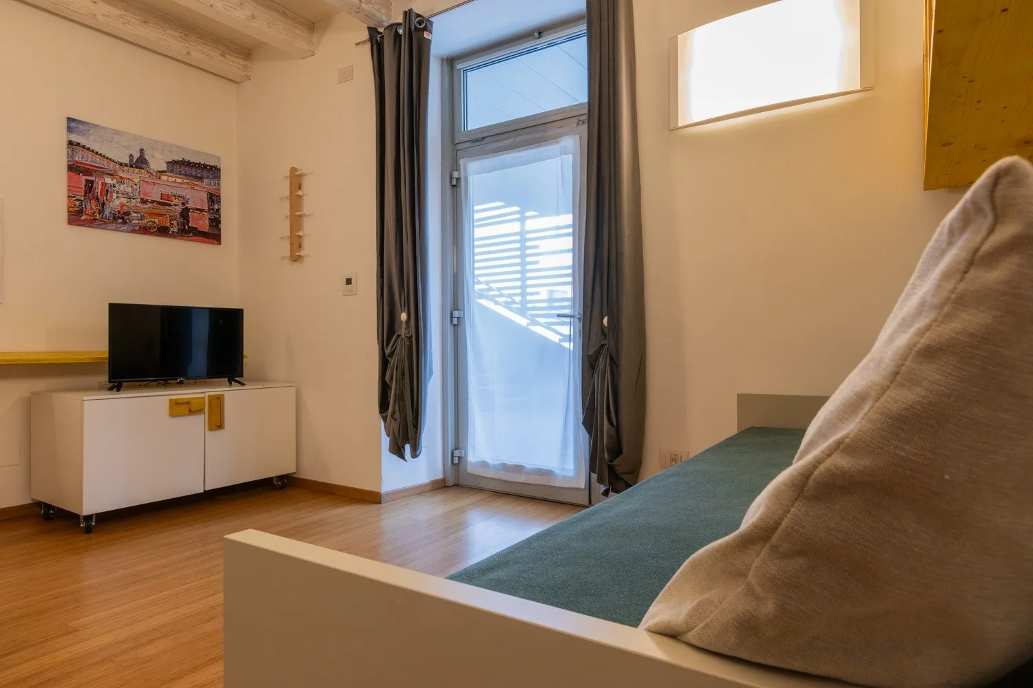 Un dormitorio con una cama, un televisor y una puerta de vidrio que da a un balcón.