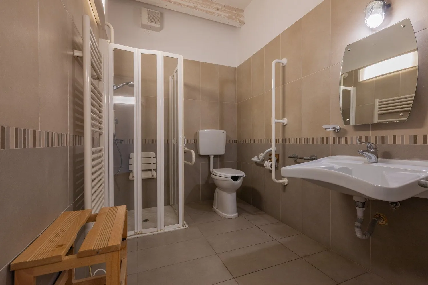 Un baño alicatado con ducha, inodoro y lavabo de pared.