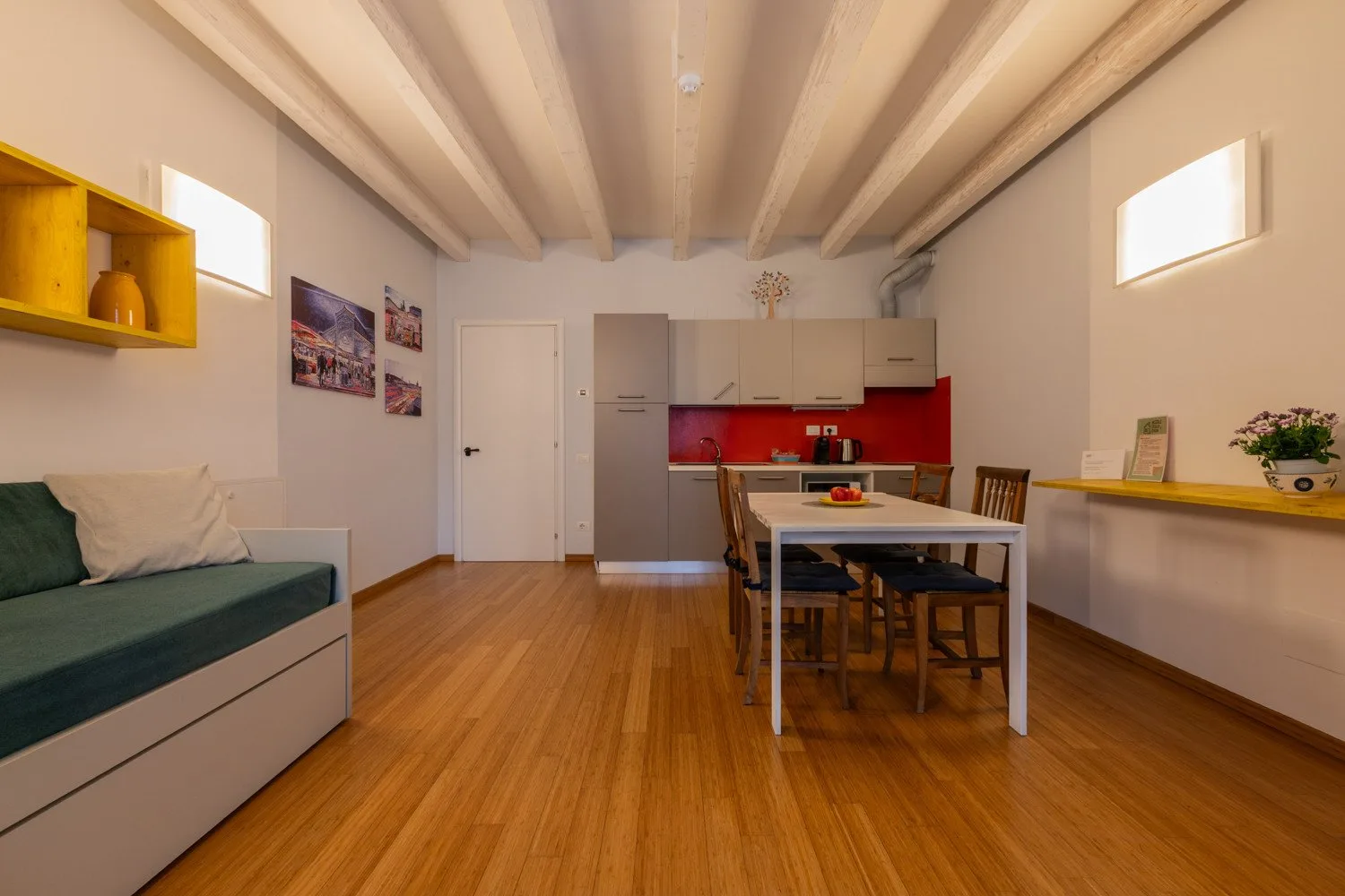 Una sala-comedor con una mesa, asientos y una cocina.