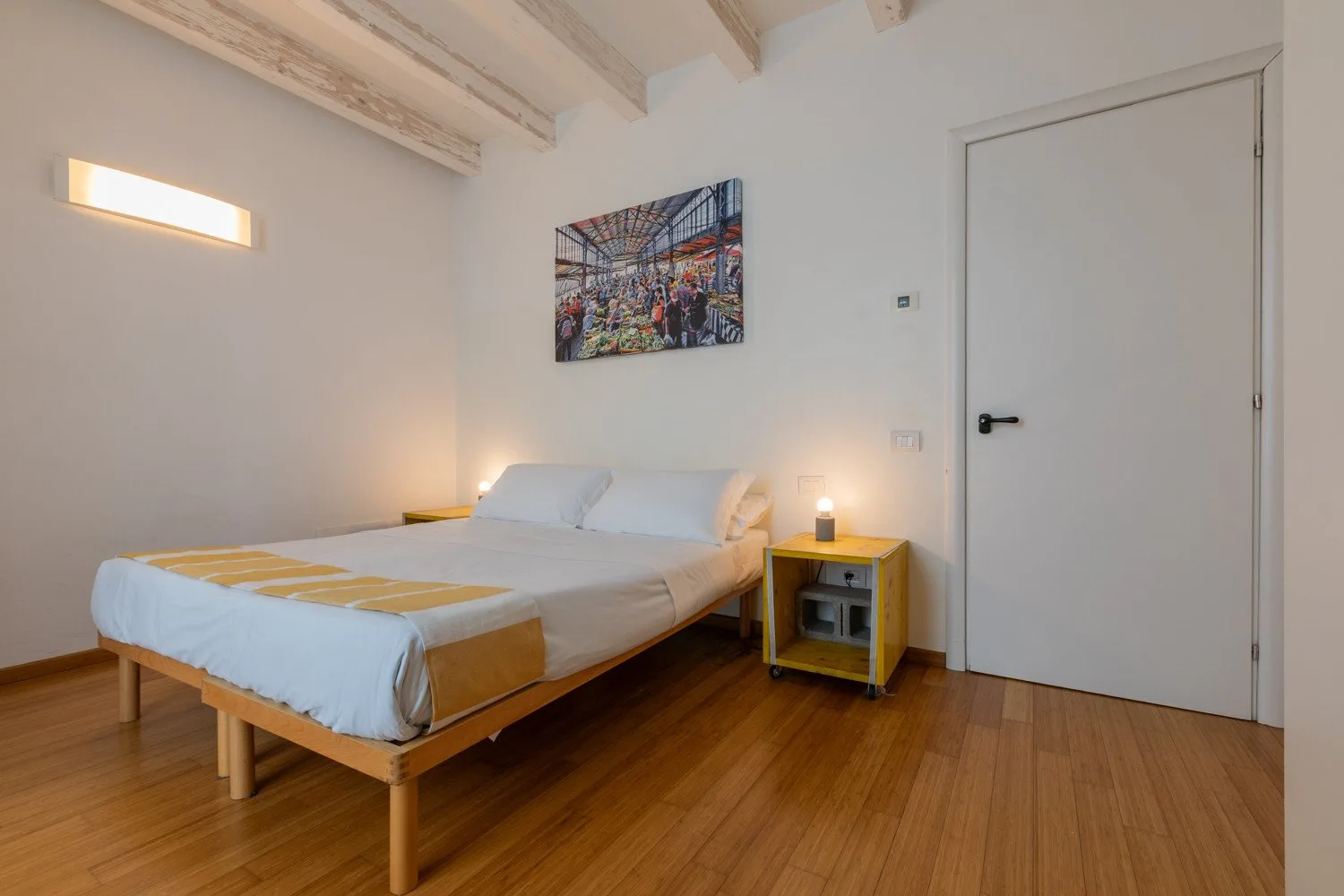 Un dormitorio con una cama, mesitas de noche y un cuadro en la pared.