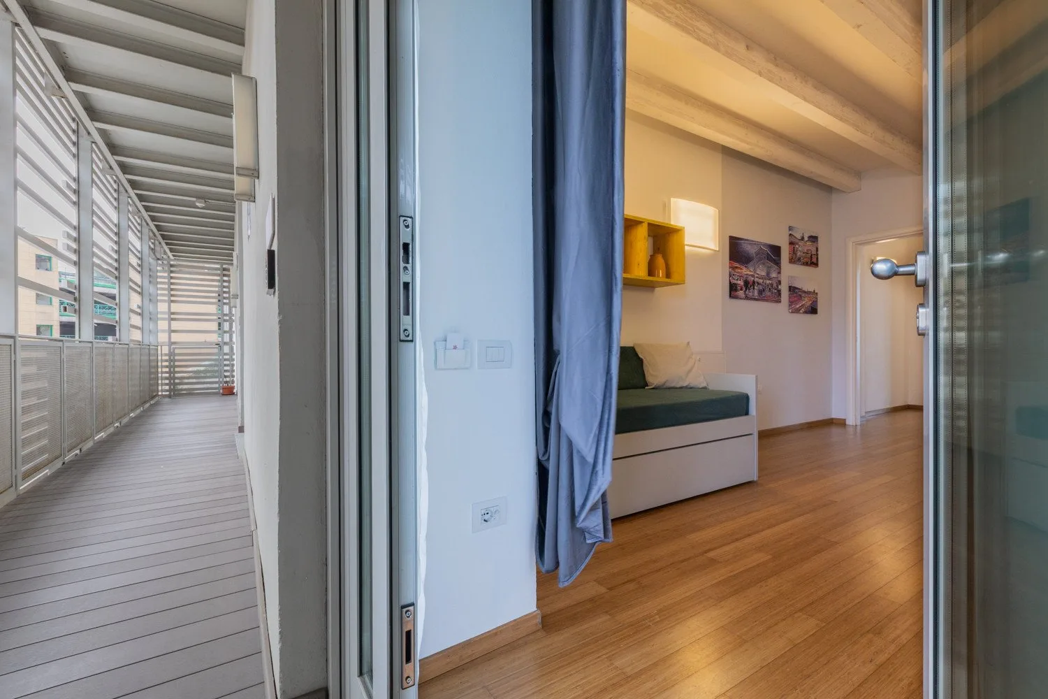 Un dormitorio con una cama, cuadros y una puerta corrediza de vidrio que da a un balcón.