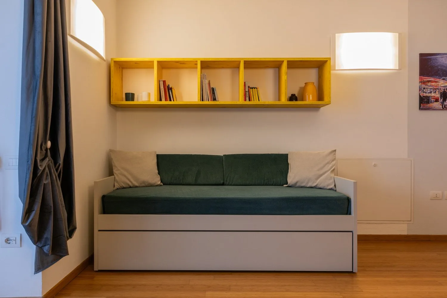 Un diván está bajo una repisa amarilla en una habitación cálidamente iluminada.