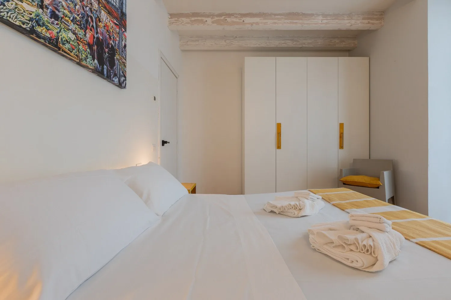 Un dormitorio con una cama grande, ropa de cama blanca y un armario.