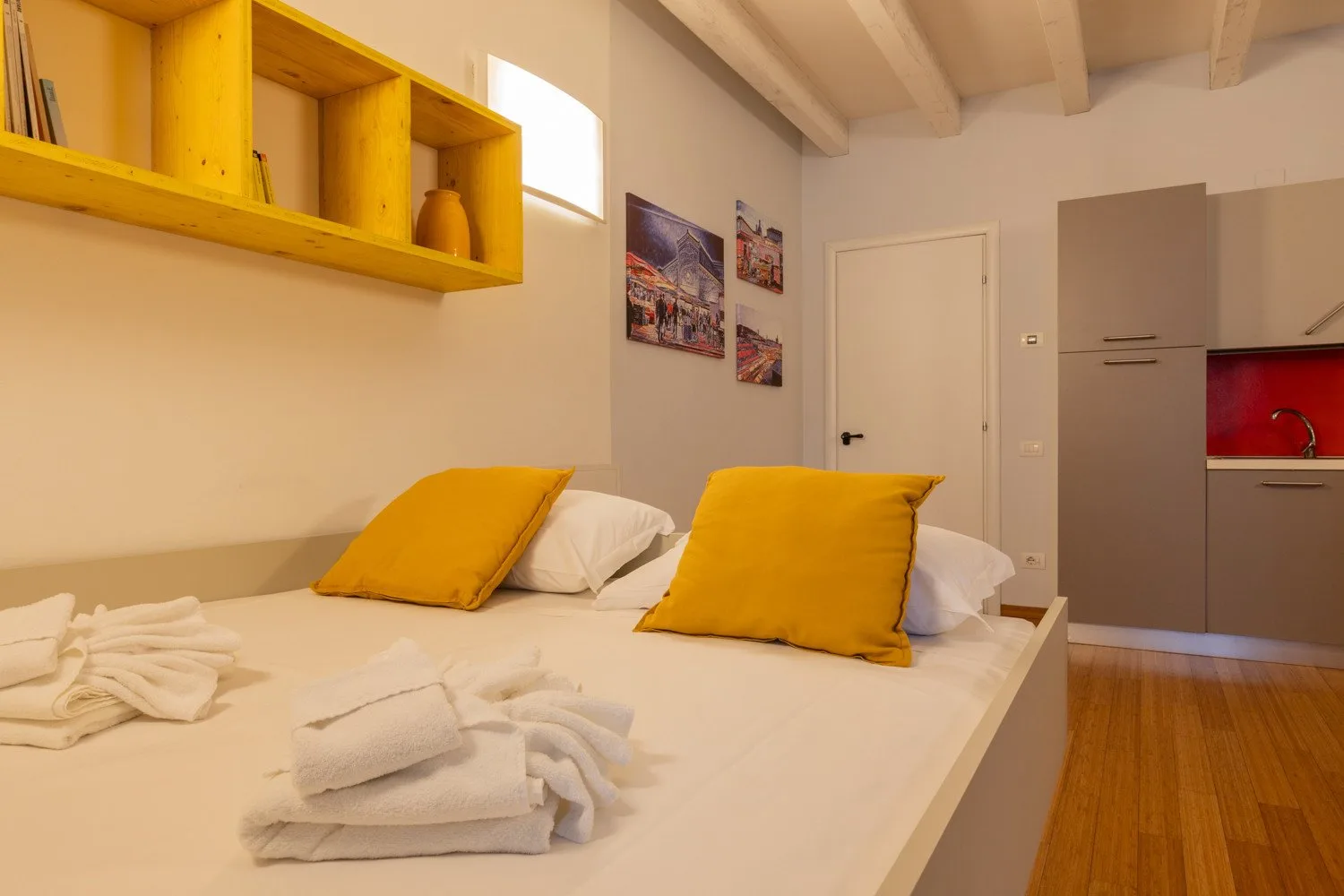 Un dormitorio con una cama vestida con ropa blanca y almohadas amarillas.