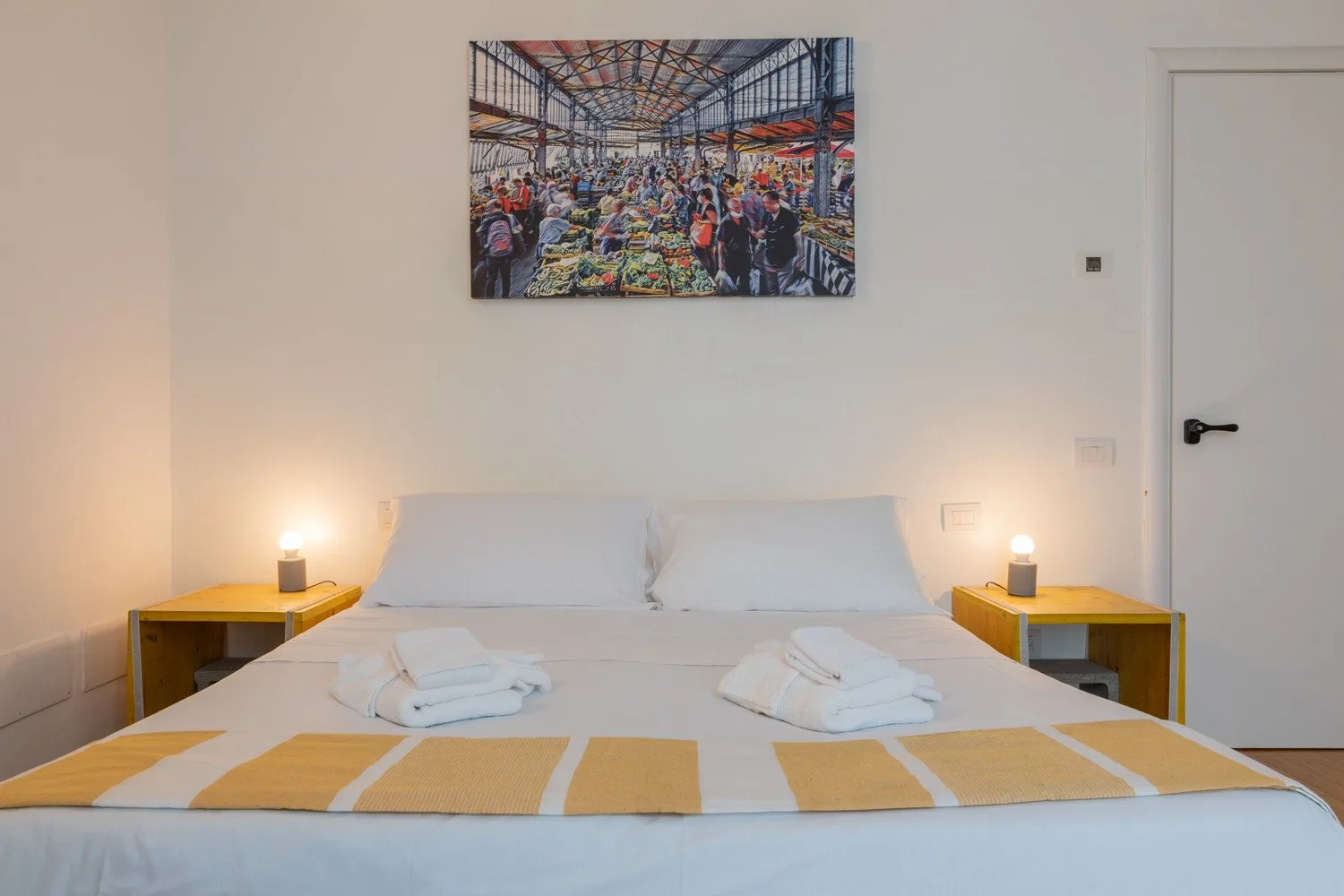 Un dormitorio con una cama bien tendida y una pintura colorida encima.