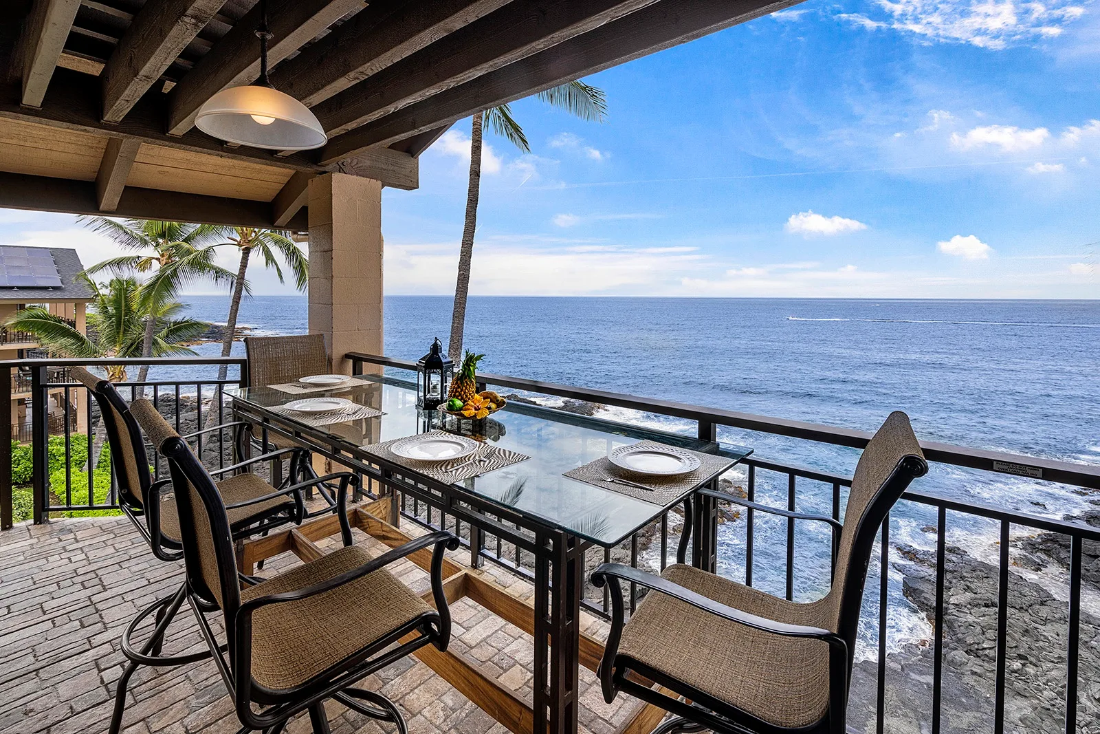 Una zona de comedor al aire libre da al océano, con una mesa y sillas en la terraza.