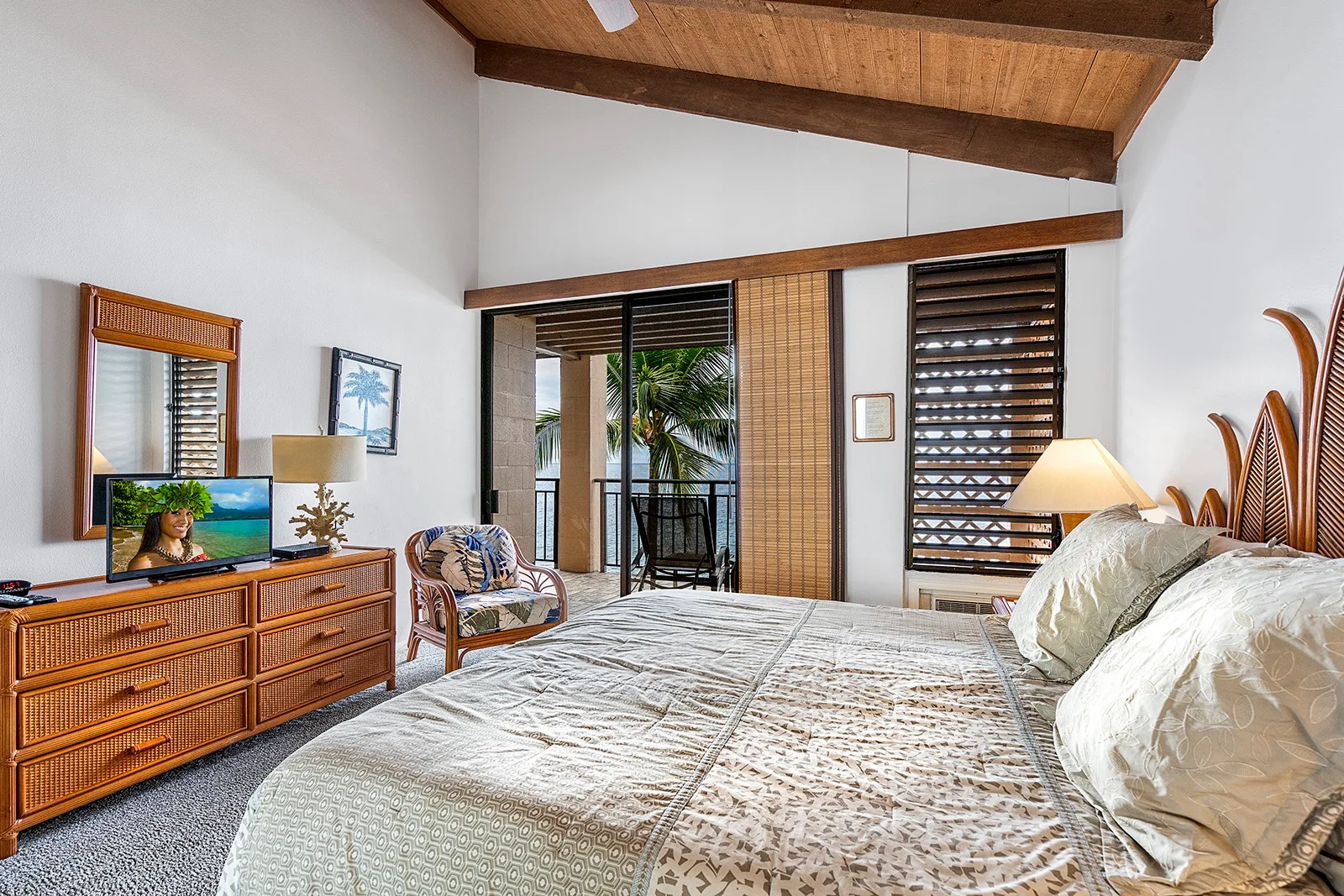 Un dormitorio con una cama grande, una cómoda de madera y puertas corredizas de vidrio.