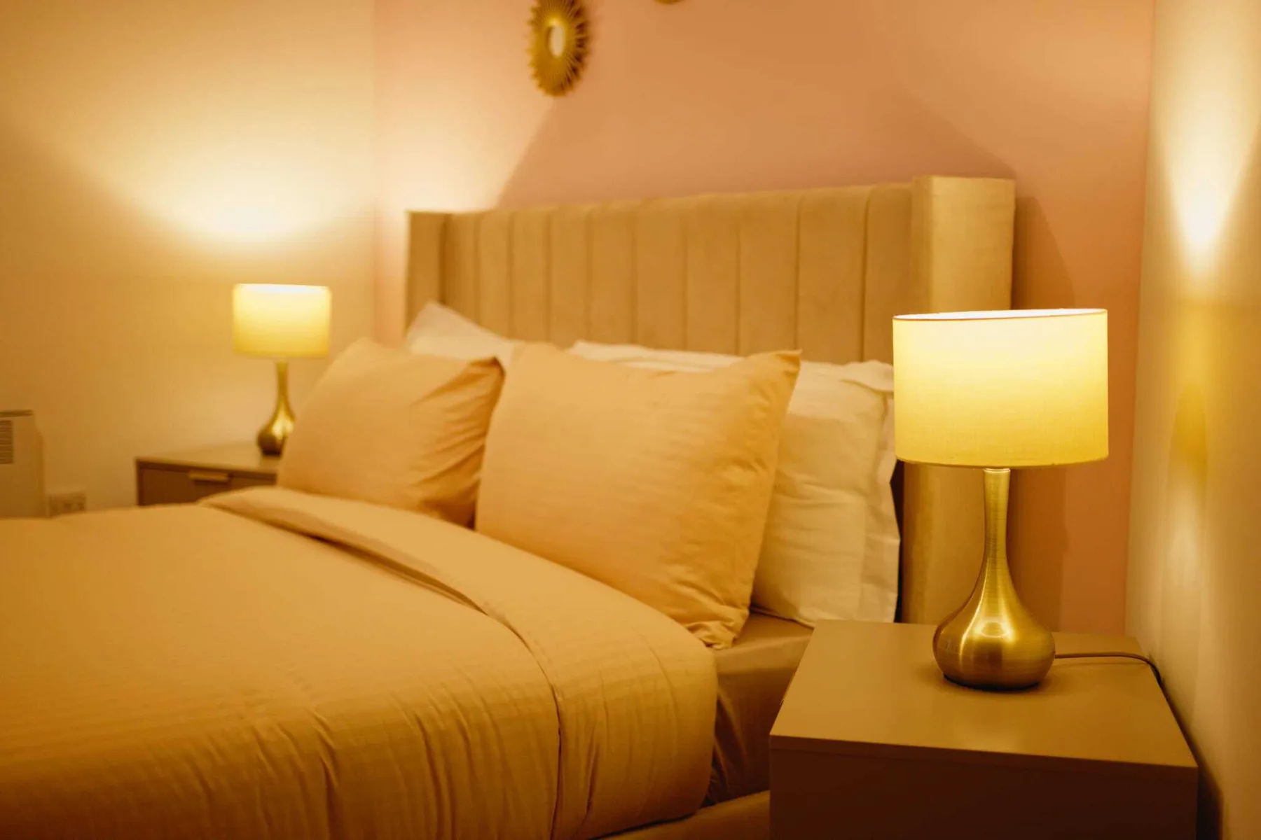 Un dormitorio con luz cálida, una cama bien hecha y lámparas de mesilla.